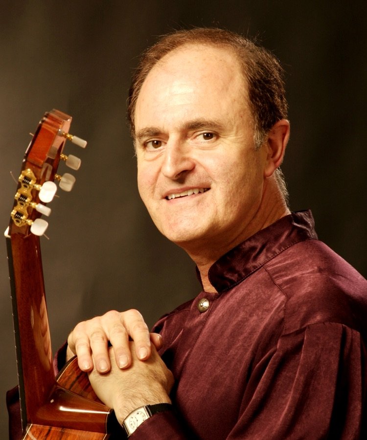 Julian Byzantine in a burgundy shirt, leaning on his guitar